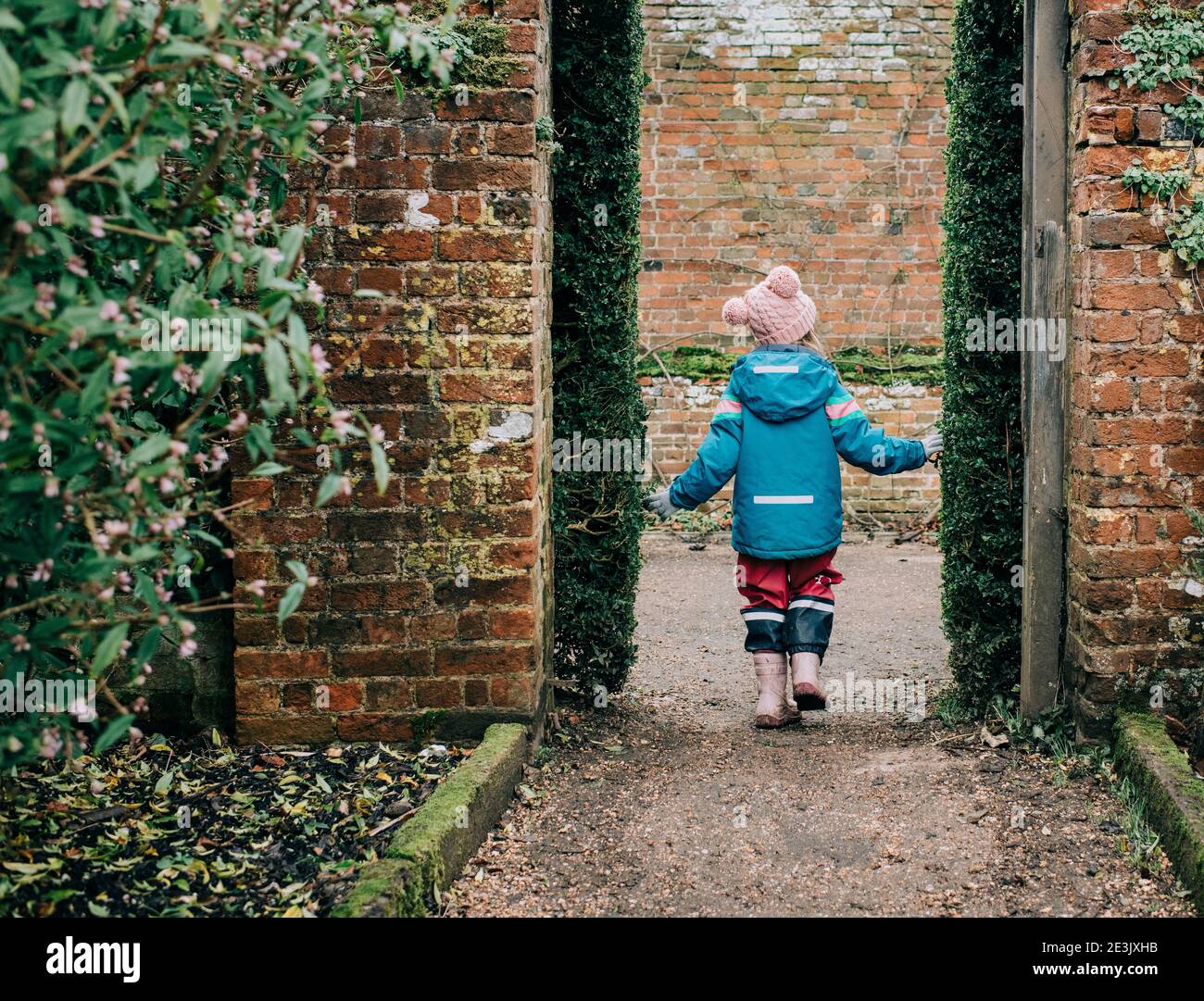 Kind, das im Winter durch einen englischen Garten spazierengeht Stockfoto