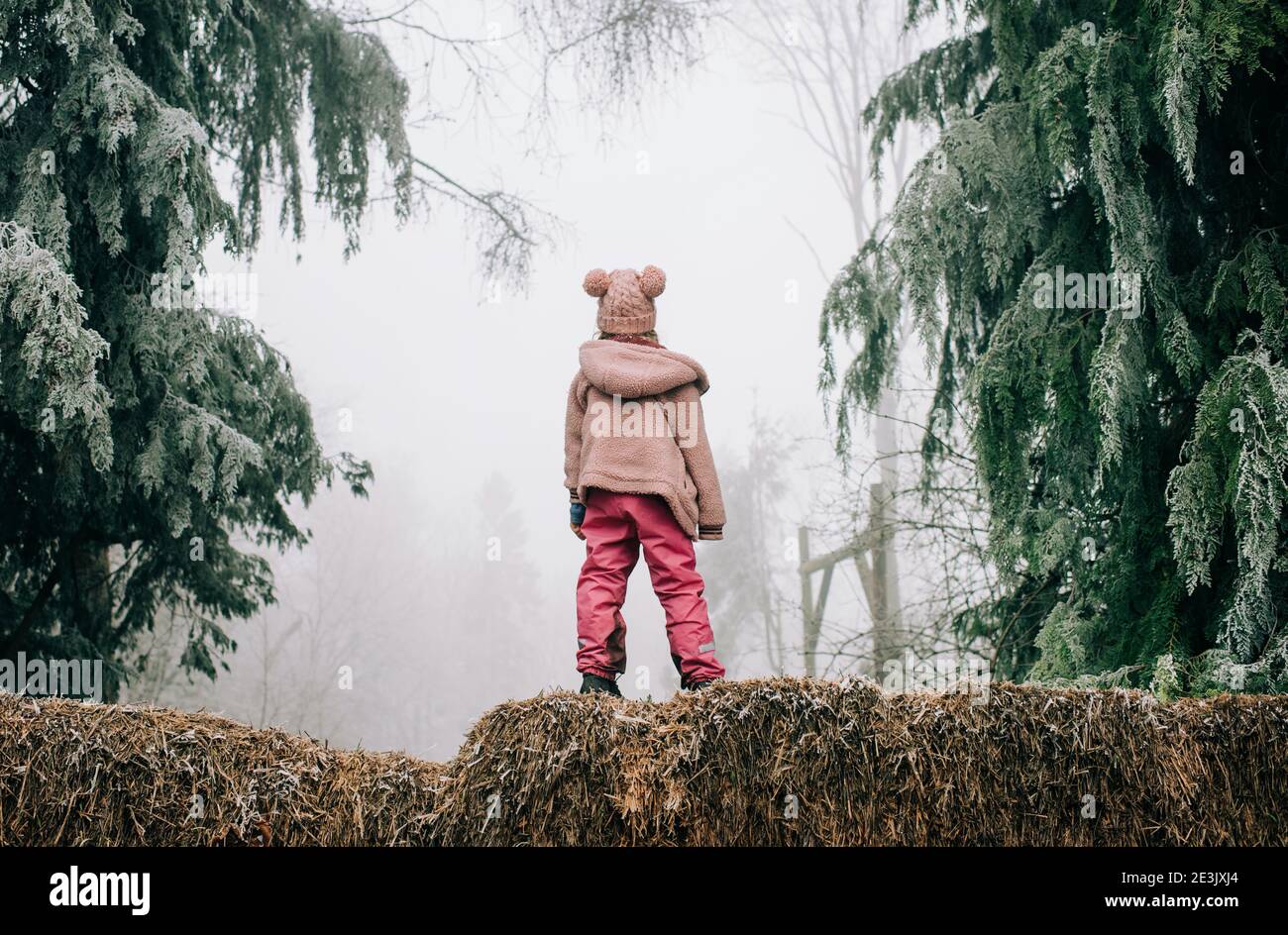 Mädchen stand im frostigen Wald und schaute in den Nebel In England Stockfoto