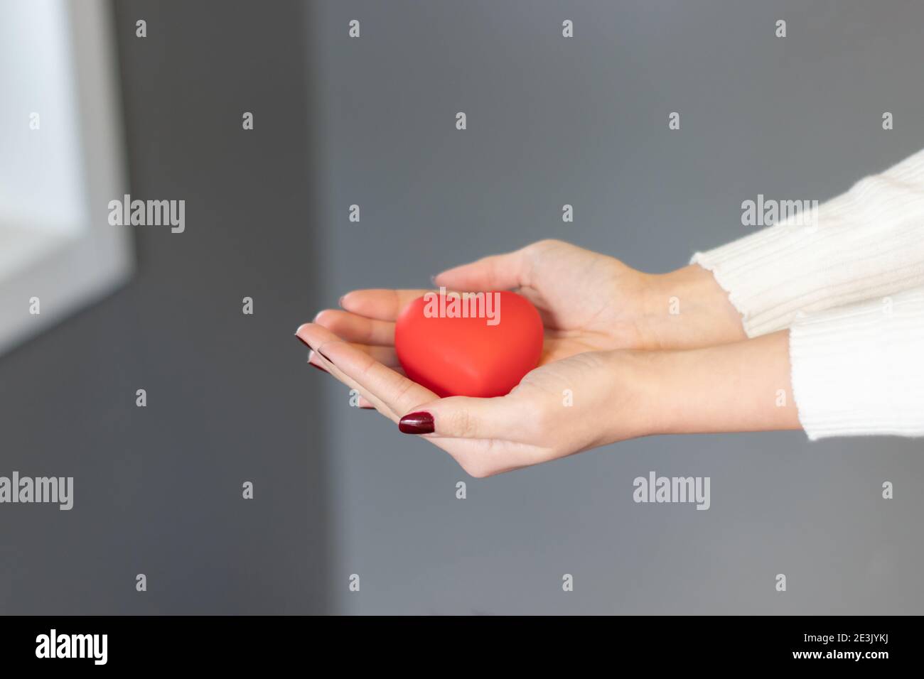 Eine Frau, die ein rotes Herz zwischen ihren Händen hält. Alles Liebe zum valentinstag, rote Farbe, Herz-Symbol, isolierte Hintergrund Stockfoto
