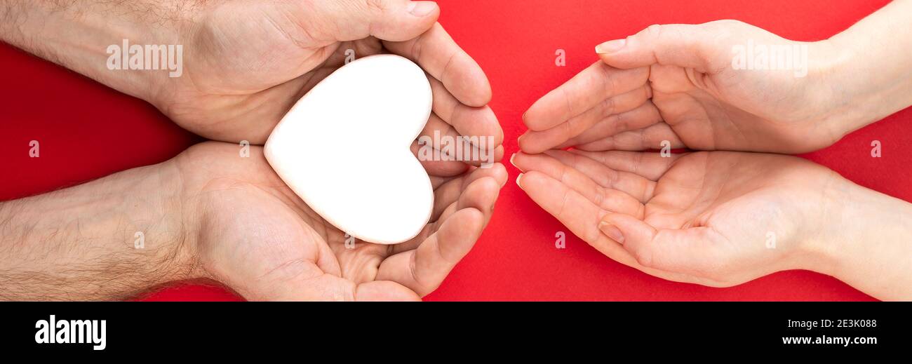 Männliche und weibliche Hände mit einem weißen Herzen, Gesundheitsversorgung, Liebe und Familie Versicherungskonzept, Welt Herz Tag, Welt Gesundheit Tag, Pflegefamilie, internatio Stockfoto