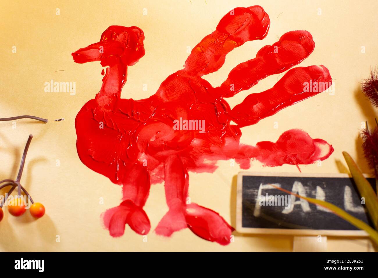 Rote Hand-pute auf Vanille-Baupapier mit orangen Beeren, Herbstlaub und einem 'FALL'-Zeichen Stockfoto