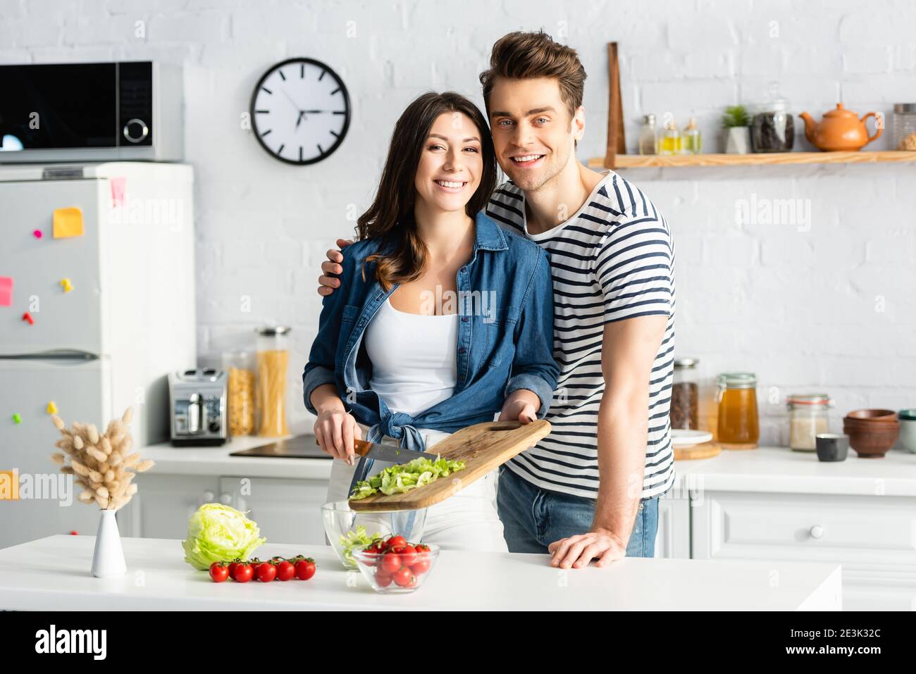Glückliches Paar bereitet Salat in der modernen Küche Stockfoto