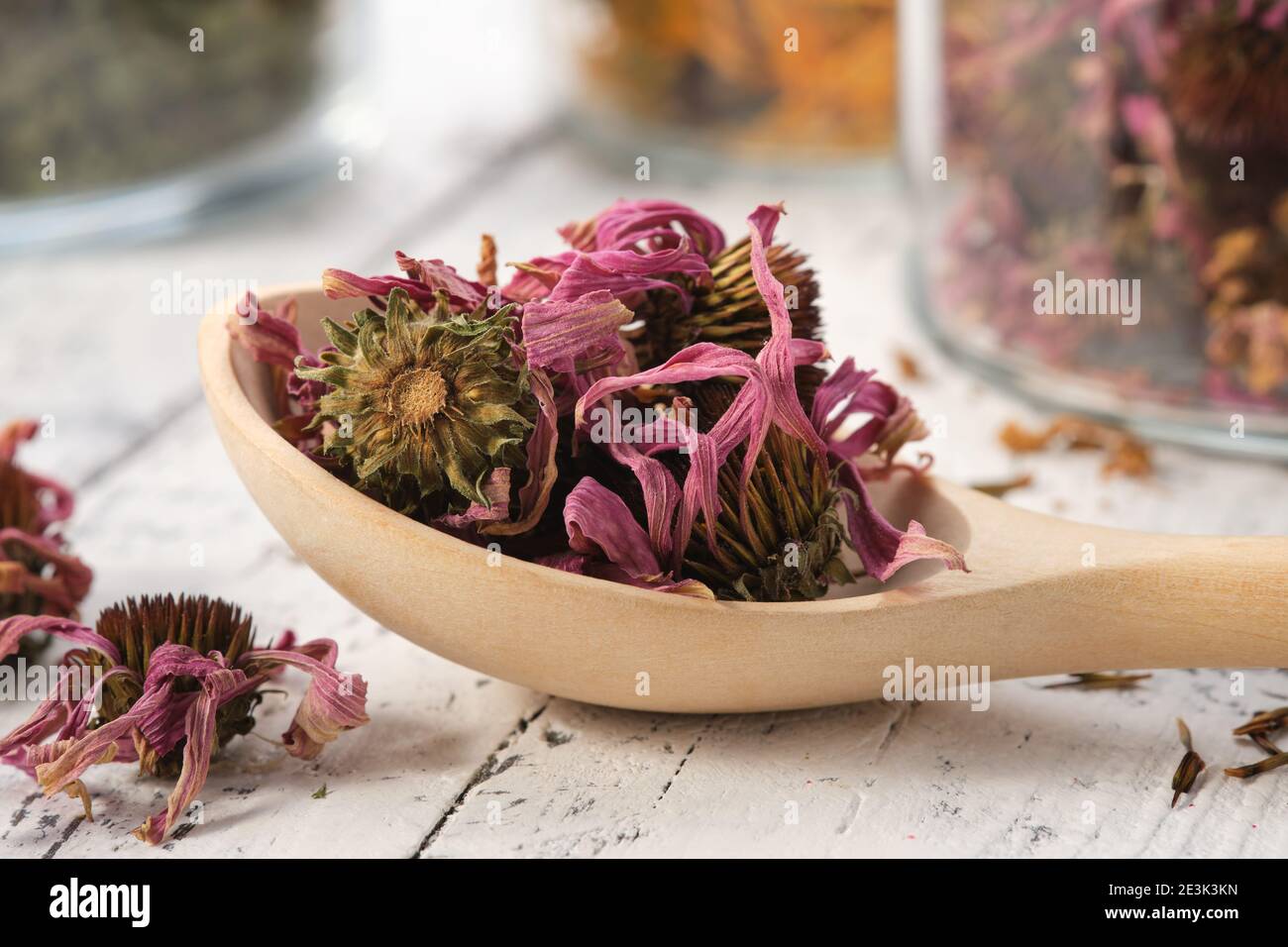 Holzlöffel gesunde Echinacea Blütenblätter und Knospen für die Zubereitung von Tee. Glasgefäße mit getrockneten Koneblüten und Heilkräutern auf dem Hintergrund. Alternative Sanitäter Stockfoto