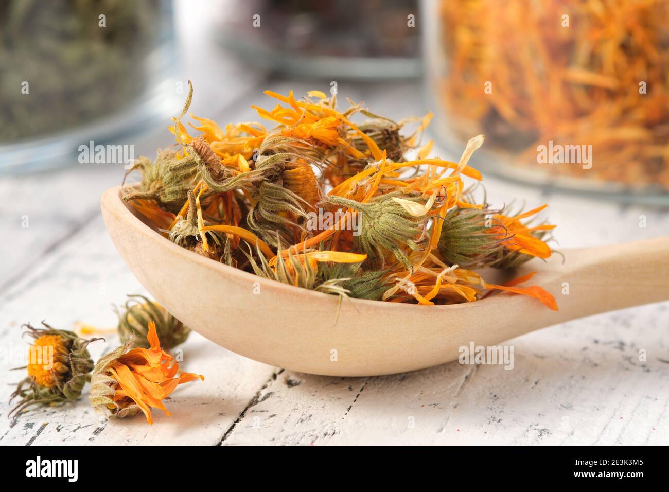 Holzlöffel getrocknete gesunde Ringelblume Blumen. Glasgefäße mit getrockneten Ringelblumenblättern und Heilkräutern auf dem Hintergrund. Alternative Medizin. Stockfoto