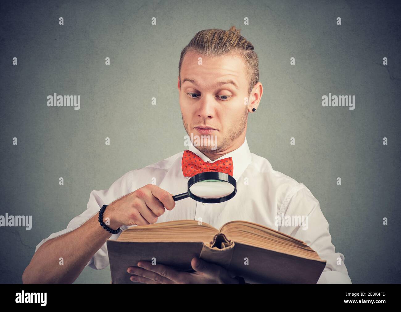 Portrait eines jungen Mannes, der ein Interessantes Buch mit liest Lupe Stockfoto