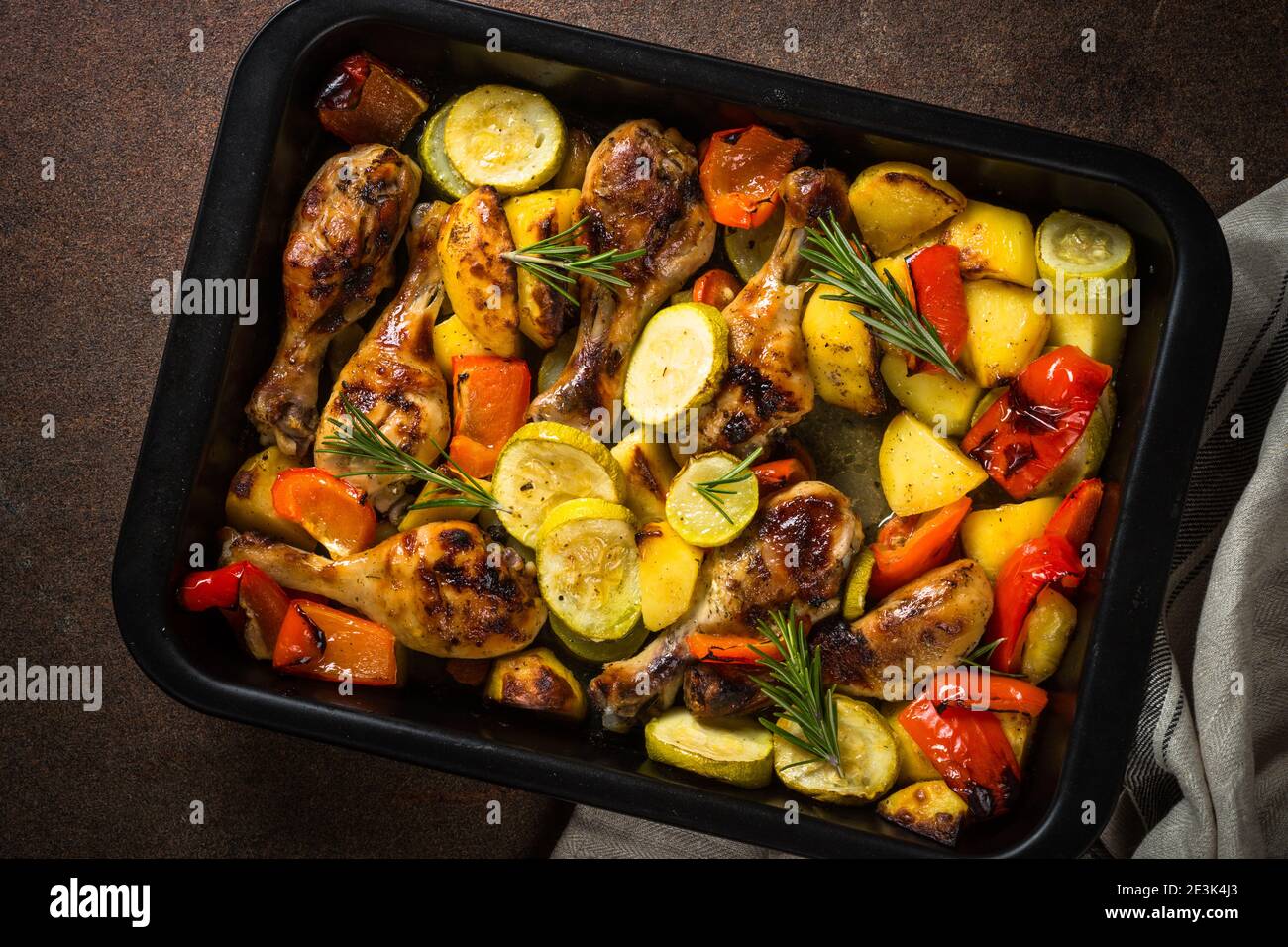 Gebackenes Huhn mit Gemüse, das im Ofen beim Backblech zubereitet wird. Stockfoto