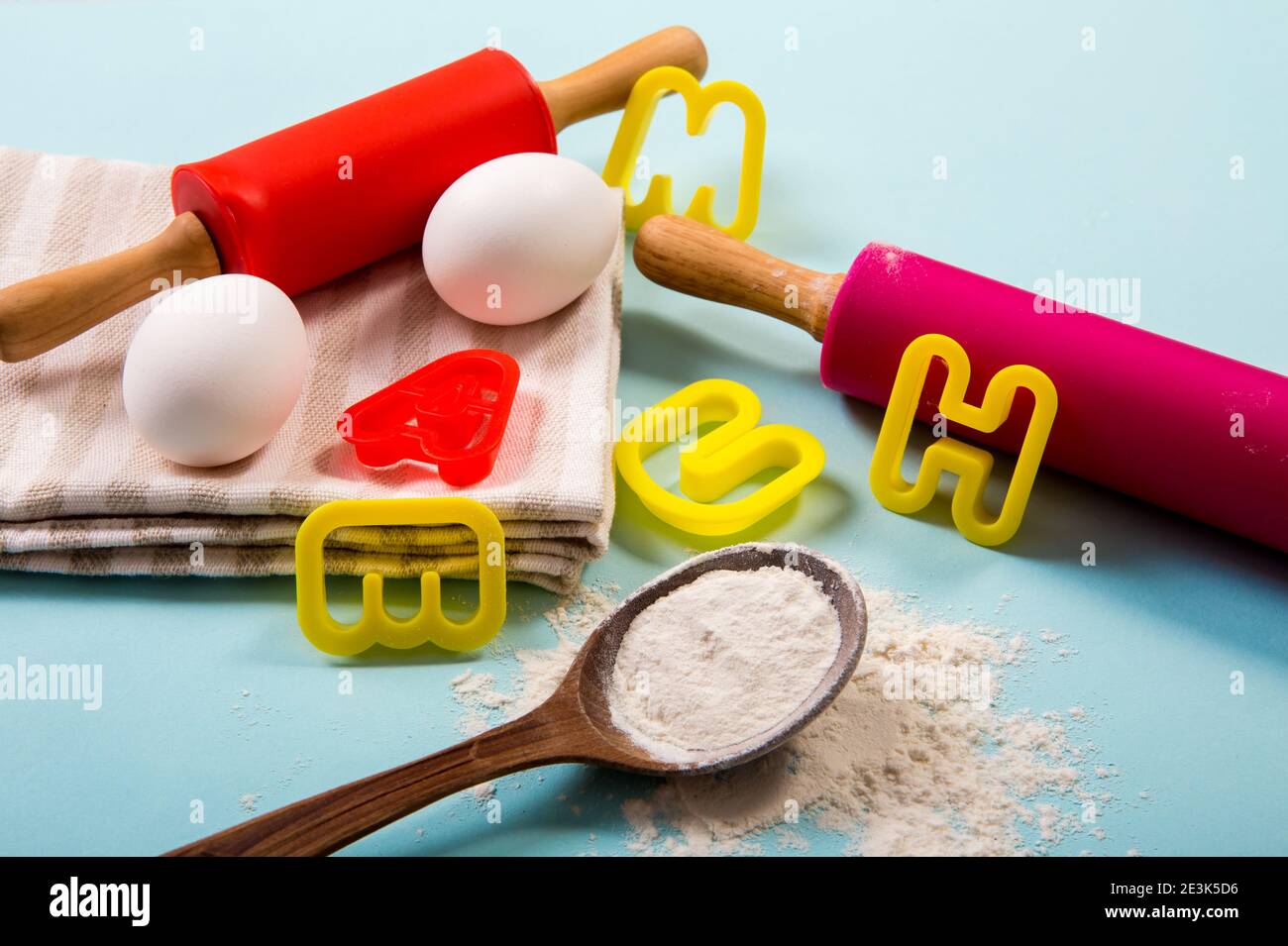 Kochkurs für Kinder Konzept. Eier, Mehl, Rollnadeln, Ausstechformen auf hellblauem Hintergrund, Studioaufnahme. Stockfoto