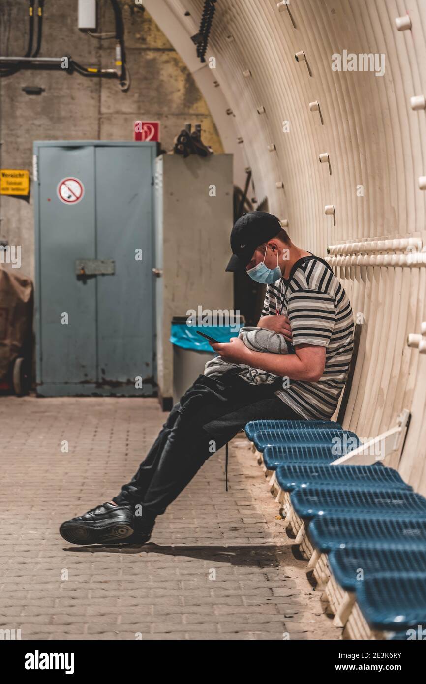 Zugspitze, Deutschland - 5. Aug 2020: Maskierter Tourist liest am Gletscherbahnhof am Telefon Stockfoto