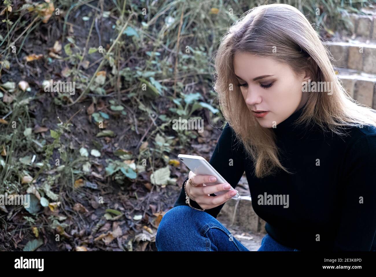 Junge Frau, die am Telefon im Park unzufrieden, SMS-Nachrichten, mit Anwendungen Stockfoto