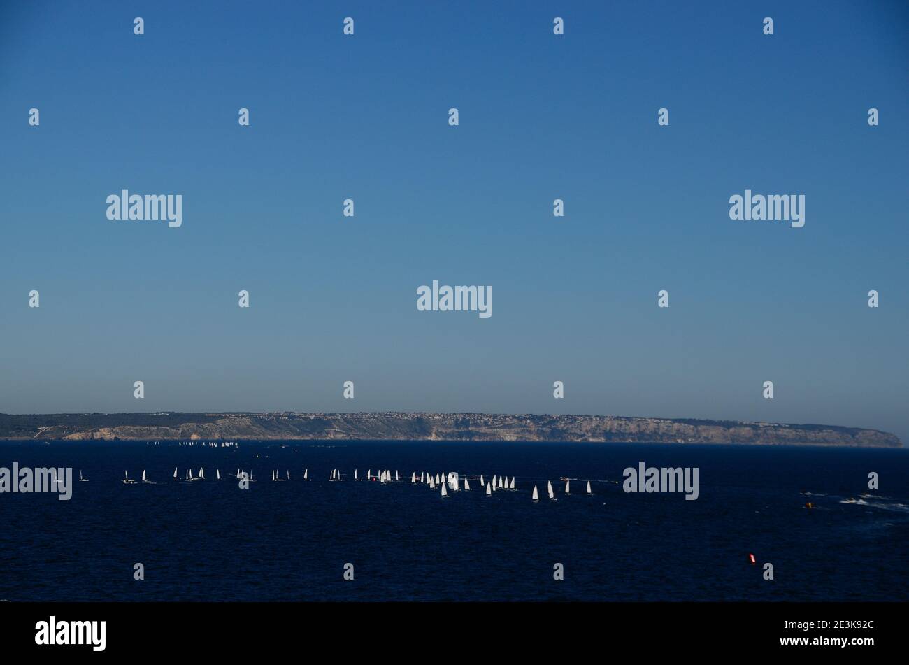 Viele weiße Segelboote mit felsiger Küste im blauen Meer Stockfoto