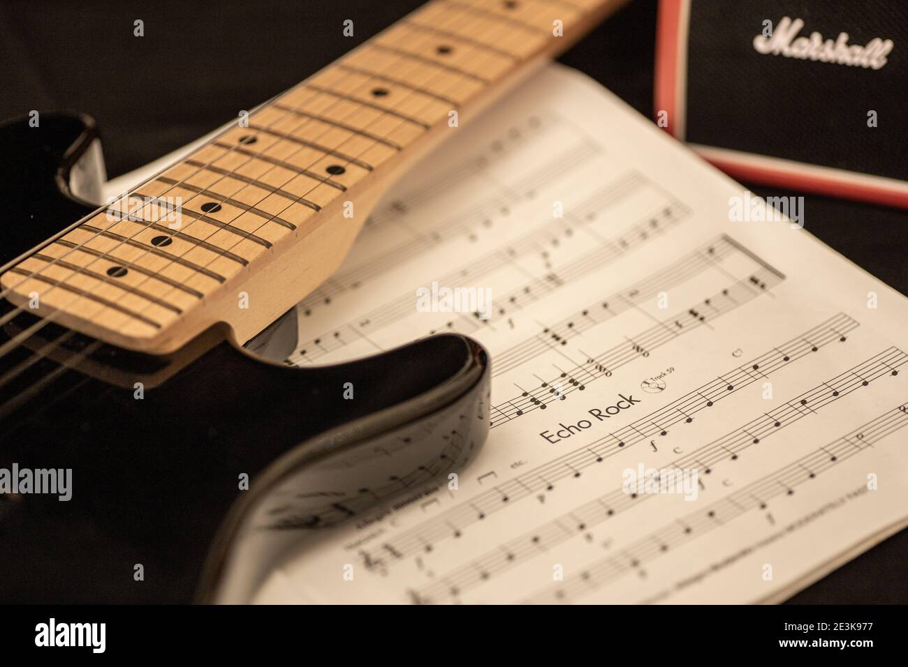 Nahaufnahme von E-Gitarre und Musikbuch mit einem Marshallverstärker im Hintergrund. Üben, komponieren oder produzieren Sie Rockmusik. Stockfoto