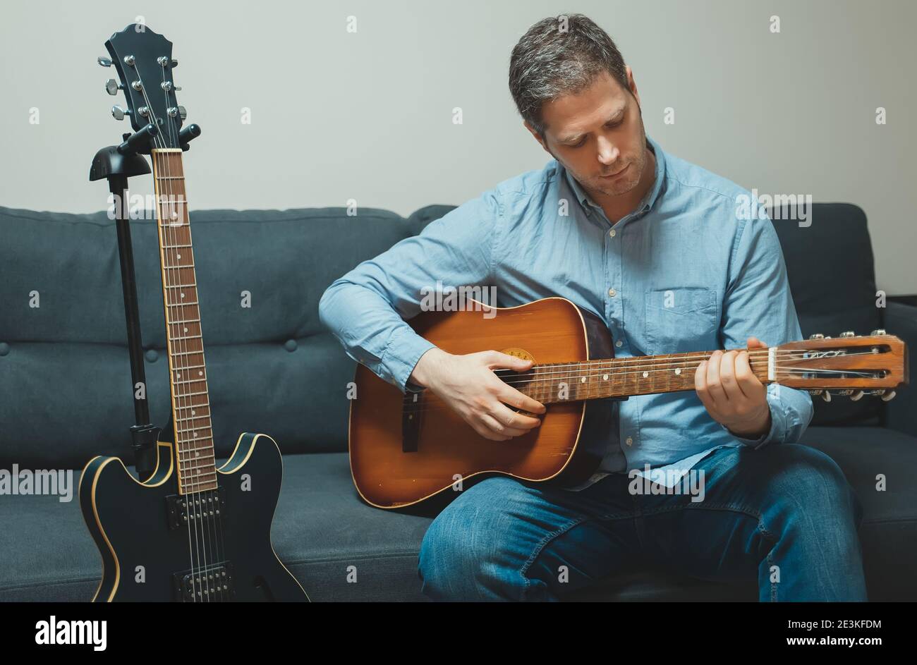 Schöner Mann, der zu Hause spanische Gitarre spielt. Stockfoto