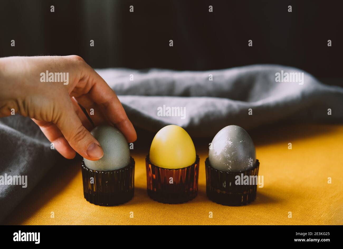 Hand Holding Bio natürlich gefärbte gelbe und graue Ostereier. Stilvolles Urlaubsdekor. Stockfoto