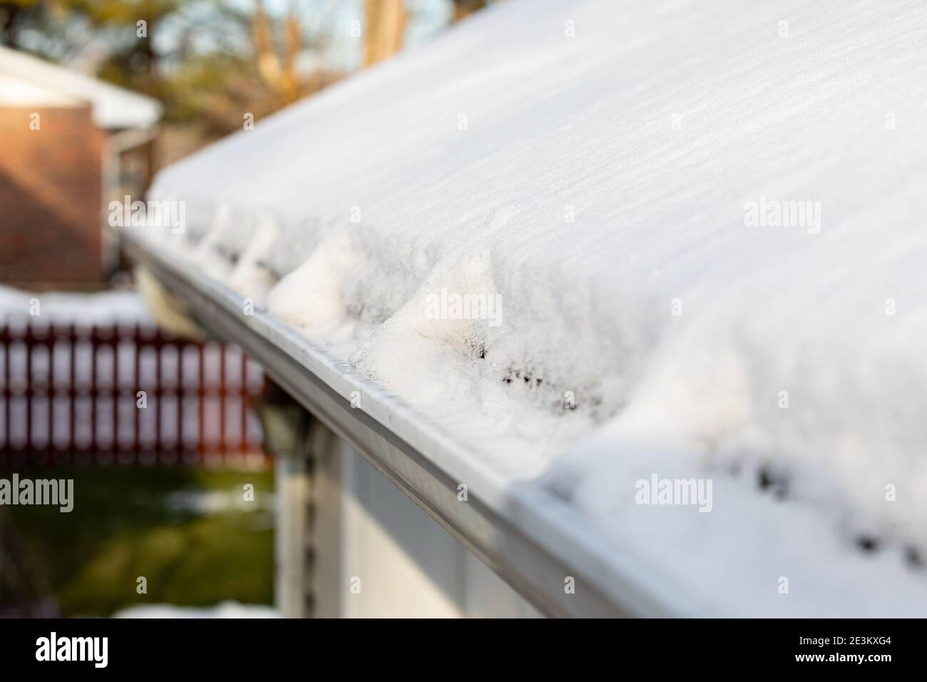 Dachrinne voller Schnee und Eis nach dem Wintersturm. Konzept von Dachschäden, Hauswartung und Reparatur. Stockfoto
