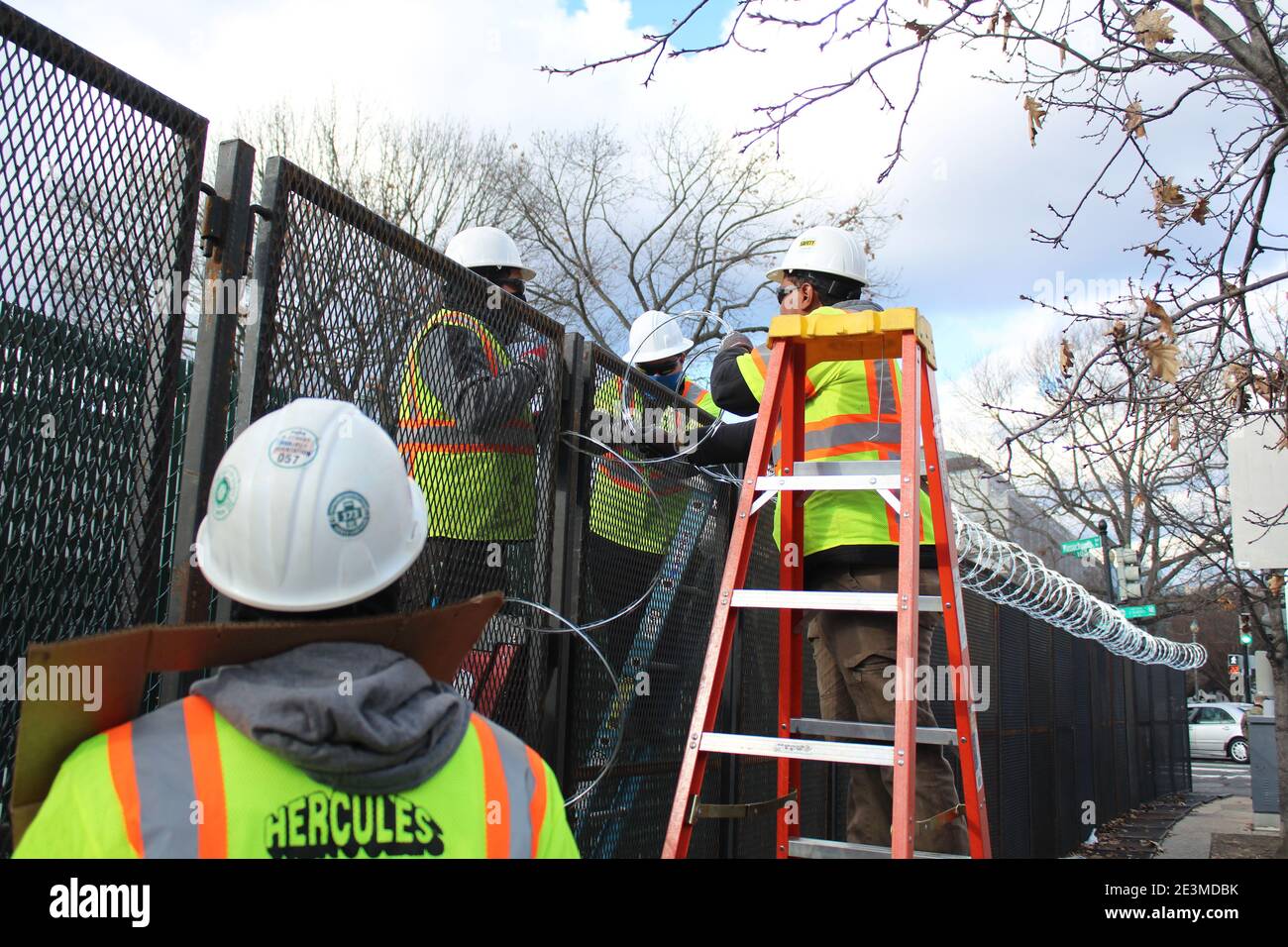 Washington DC, District of Columbia, USA. Januar 2021. Mit Joe Bidens Amtseinführung kämpfen die Bewohner von Washington DC darum, sich an die verschlossene US-Hauptstadt anzupassen. Diese Arbeiter mit fluoreszierenden Jacken gekleidet und ihre Köpfe mit Hüten bedeckt installieren Rollen Stacheldraht über den Zäunen. Nicht weniger als 25,000 Truppen, 4,000 Marshalls, Capitol Police, FBI-Spezialeinheiten wurden in der ganzen Stadt eingesetzt, als die Bedrohungen nach dem tödlichen Angriff auf Capitol Hill am 6. Januar ihren Höhepunkt erreichten. Quelle: Marie Le BLE/ZUMA Wire/Alamy Live News Stockfoto