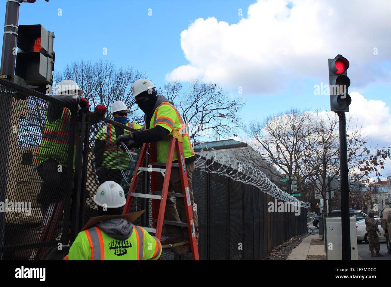Washington DC, District of Columbia, USA. Januar 2021. Mit Joe Bidens Amtseinführung kämpfen die Bewohner von Washington DC darum, sich an die verschlossene US-Hauptstadt anzupassen. Diese Arbeiter mit fluoreszierenden Jacken gekleidet und ihre Köpfe mit Hüten bedeckt installieren Rollen Stacheldraht über den Zäunen. Nicht weniger als 25,000 Truppen, 4,000 Marshalls, Capitol Police, FBI-Spezialeinheiten wurden in der ganzen Stadt eingesetzt, als die Bedrohungen nach dem tödlichen Angriff auf Capitol Hill am 6. Januar ihren Höhepunkt erreichten. Quelle: Marie Le BLE/ZUMA Wire/Alamy Live News Stockfoto