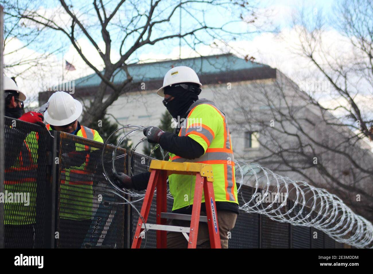 Washington DC, District of Columbia, USA. Januar 2021. Mit Joe Bidens Amtseinführung kämpfen die Bewohner von Washington DC darum, sich an die verschlossene US-Hauptstadt anzupassen. Diese Arbeiter mit fluoreszierenden Jacken gekleidet und ihre Köpfe mit Hüten bedeckt installieren Rollen Stacheldraht über den Zäunen. Nicht weniger als 25,000 Truppen, 4,000 Marshalls, Capitol Police, FBI-Spezialeinheiten wurden in der ganzen Stadt eingesetzt, als die Bedrohungen nach dem tödlichen Angriff auf Capitol Hill am 6. Januar ihren Höhepunkt erreichten. Quelle: Marie Le BLE/ZUMA Wire/Alamy Live News Stockfoto