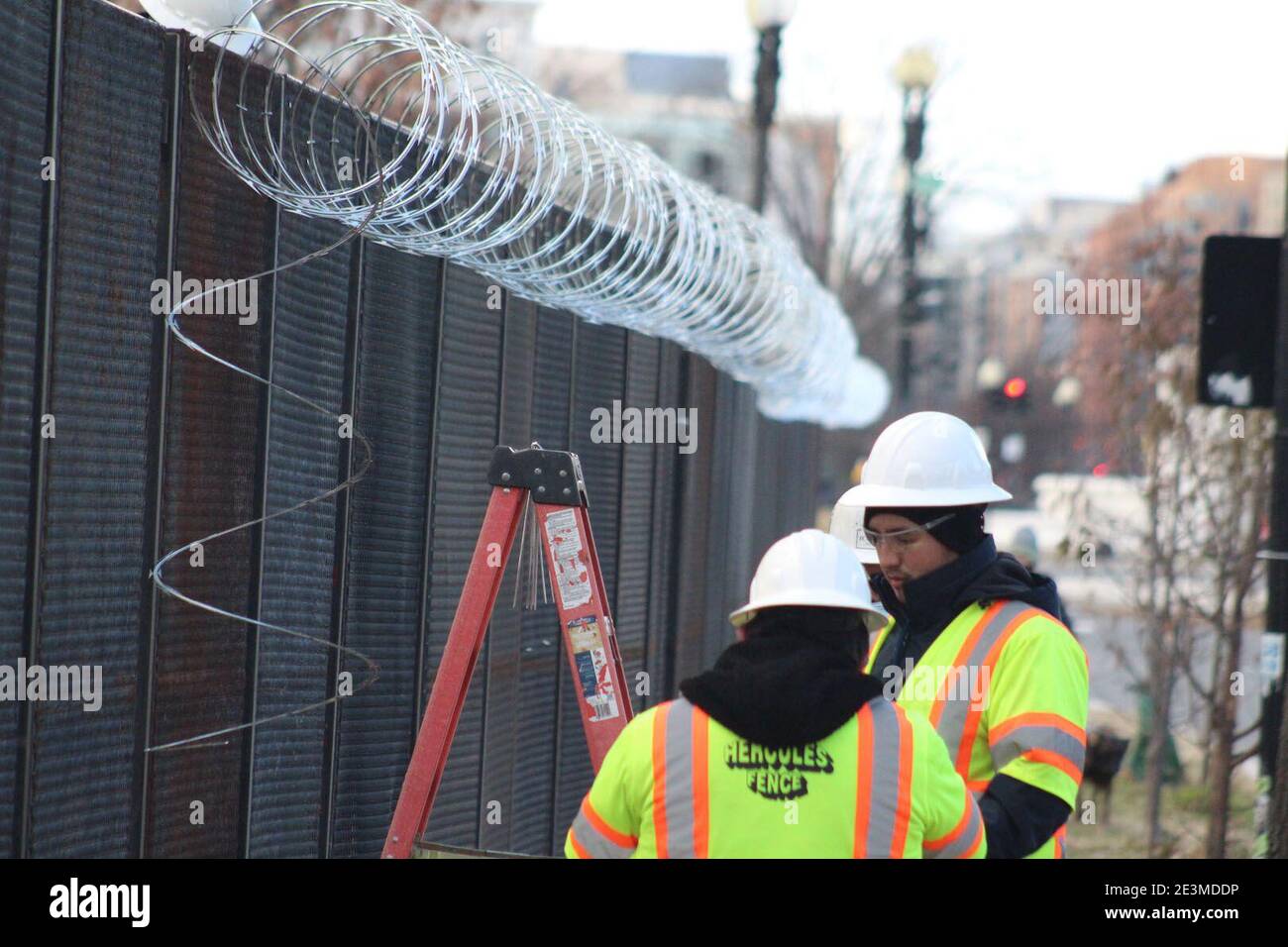Washington DC, District of Columbia, USA. Januar 2021. Diese Arbeiter mit fluoreszierenden Jacken gekleidet und ihre Köpfe mit Hüten bedeckt installieren Rollen Stacheldraht über den Zäunen. Nicht weniger als 25,000 Truppen, 4,000 Marshalls, Capitol Police, FBI-Spezialeinheiten wurden in der ganzen Stadt eingesetzt, als die Bedrohungen nach dem tödlichen Angriff auf Capitol Hill am 6. Januar ihren Höhepunkt erreichten. Quelle: Marie Le BLE/ZUMA Wire/Alamy Live News Stockfoto
