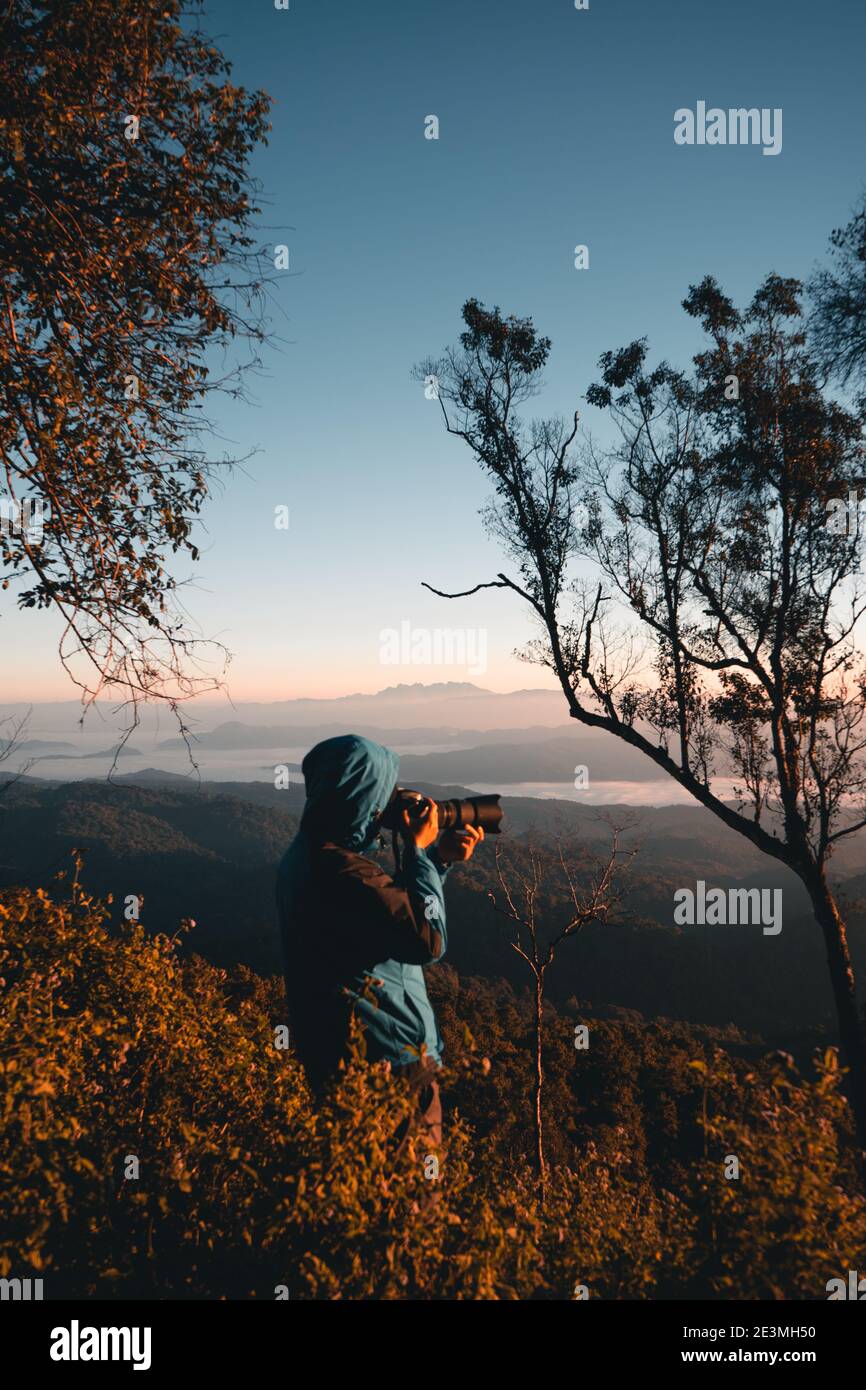 Landschaftsfotograf beim Fotografieren von Wald und Bergen am Morgen. Stockfoto