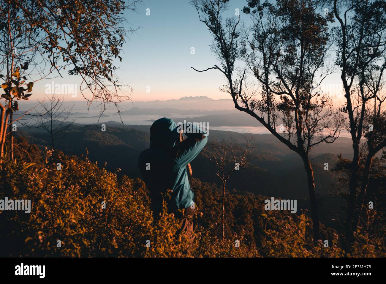 Landschaftsfotograf beim Fotografieren von Wald und Bergen am Morgen. Stockfoto