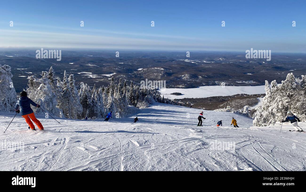 Panorama-Luftaufnahme von Mont Tremblant und See im Winter mit Skifahrern auf Piste Abfahrt, Quebec, Kanada Stockfoto