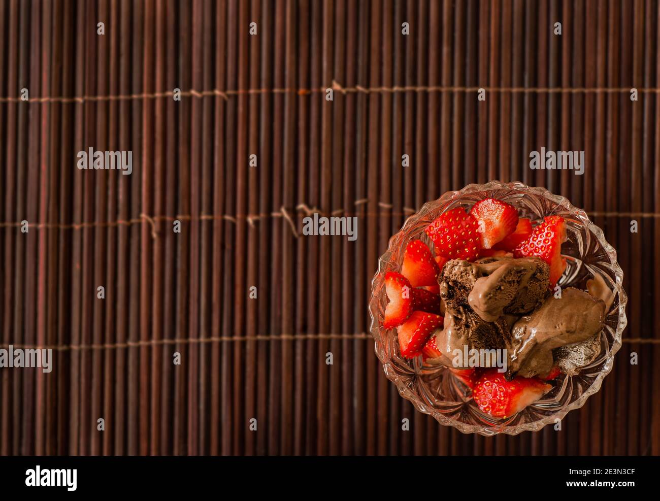 Erdbeeren und Schokoladeneis in einer Kristallschale Eine Bambusmatte Stockfoto