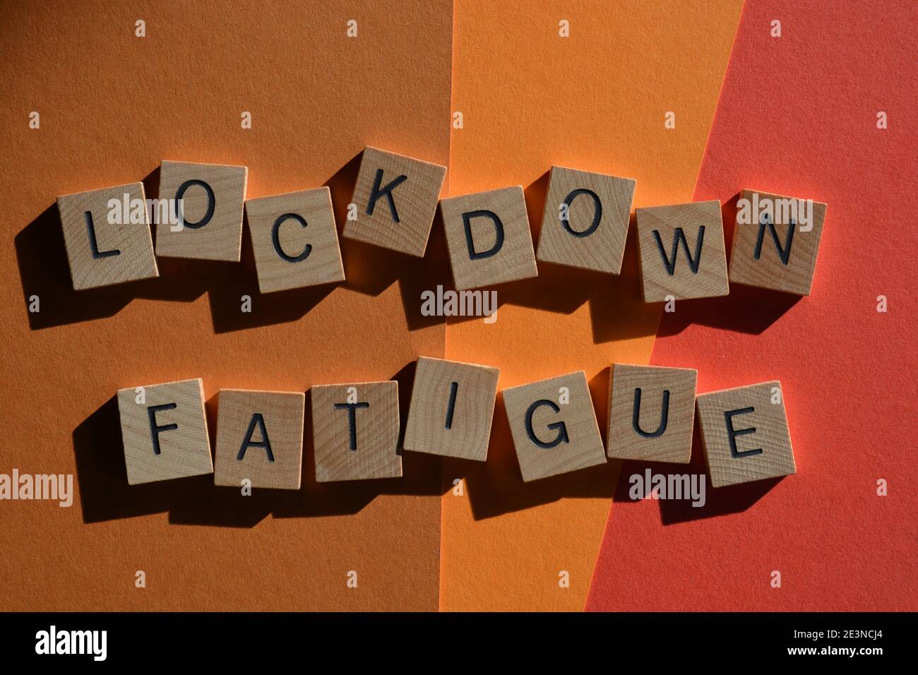 Lockdown Müdigkeit, Wörter in Holzalphabet Buchstaben isoliert auf rotem und orangefarbenem Hintergrund Stockfoto