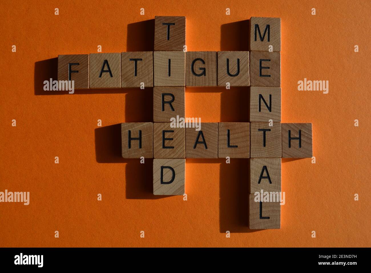 Mental, Gesundheit, müde, Müdigkeit, Wörter in Alphabet Buchstaben in Kreuzworträtsel auf orangefarbenem Hintergrund isoliert Stockfoto