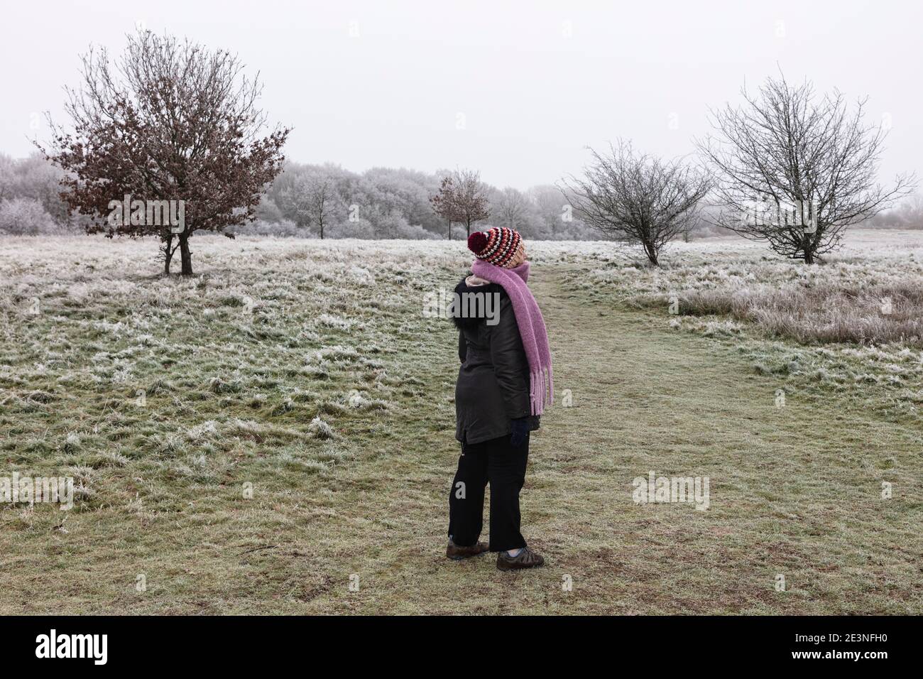 Lady steht auf kalt frostigen Ditchling Common East Sussex, warm eingewickelt Stockfoto