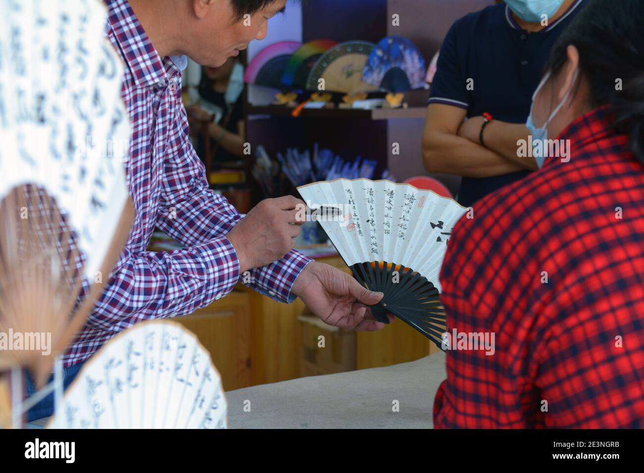 Ein chinesischer Kunsthandwerker erklärt einem Kunden in Shaoxing, China, sein Design. Der Kunde hat möglicherweise nach einem bestimmten Design gefragt. Stockfoto