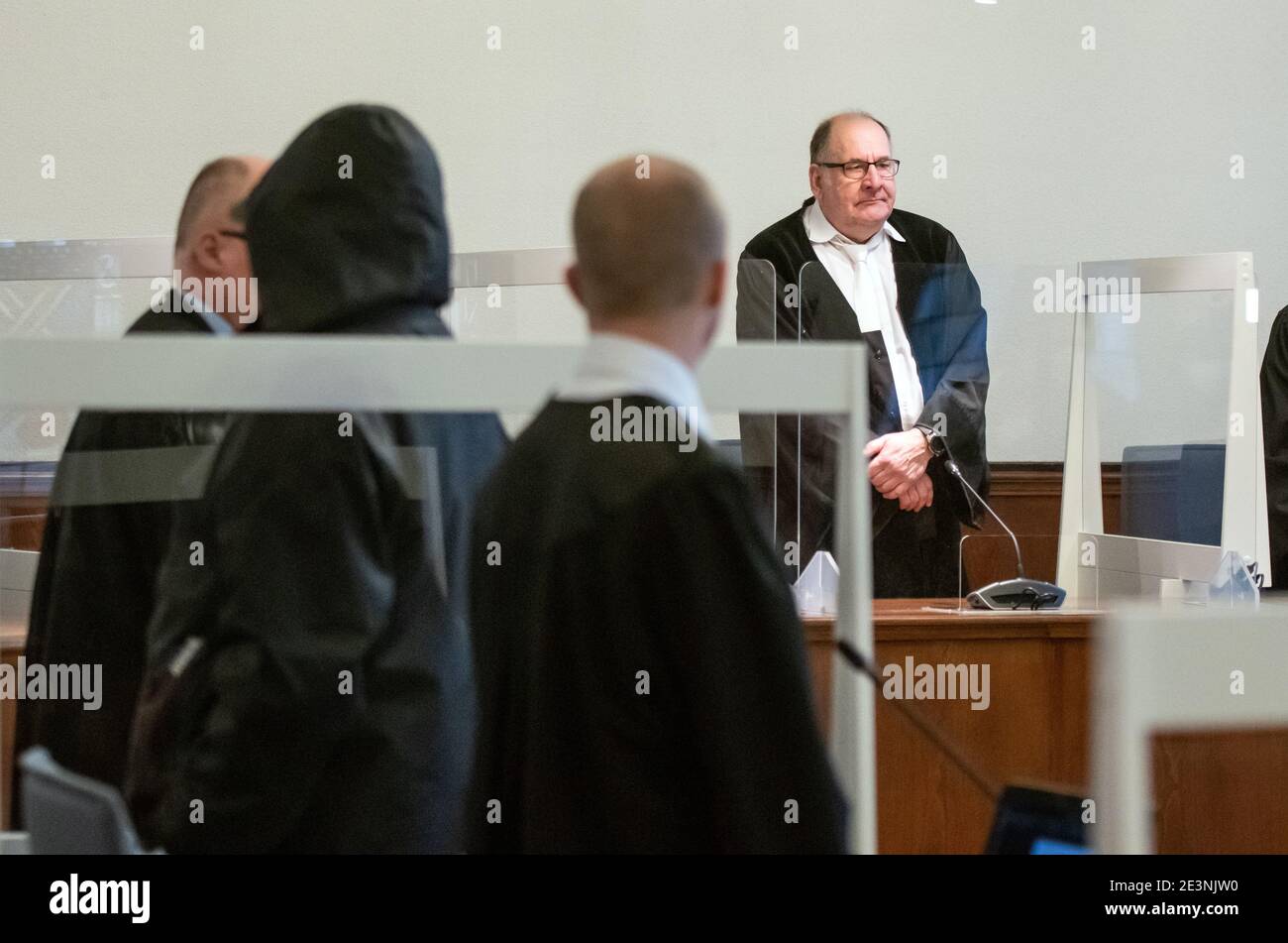 20. Januar 2021, Nordrhein-Westfalen, Dortmund: Der Vorsitzende Richter Thomas Kelm (r) steht im Landgericht zwischen Plexiglas-Scheiben zum Schutz vor Infektionen, während sich der Angeklagte (2. V.l.) zwischen seinen Anwälten abwendet. Im Herbst 1993 wurde in Dortmund eine 16-jährige Schülerin erwürgt. Der Angeklagte wurde im Sommer 2018 verhaftet. Er wird durch DNA-Spuren belastet, leugnet aber das Verbrechen. Da das Verfahren nicht unverzüglich wieder aufgenommen wurde, wurde der Angeklagte im Juli trotz dringenden Mordverdachts aus der Haft entlassen. Foto: Bernd Thissen/dpa - ACHTUNG: Person(en) haben Stockfoto