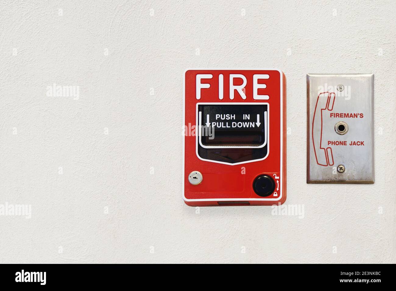 Feueralarm-Alarmverantwortlicher und Fireman's Phone Jack auf White Cement Gipswand mit Copy Space for Security Konzept Stockfoto