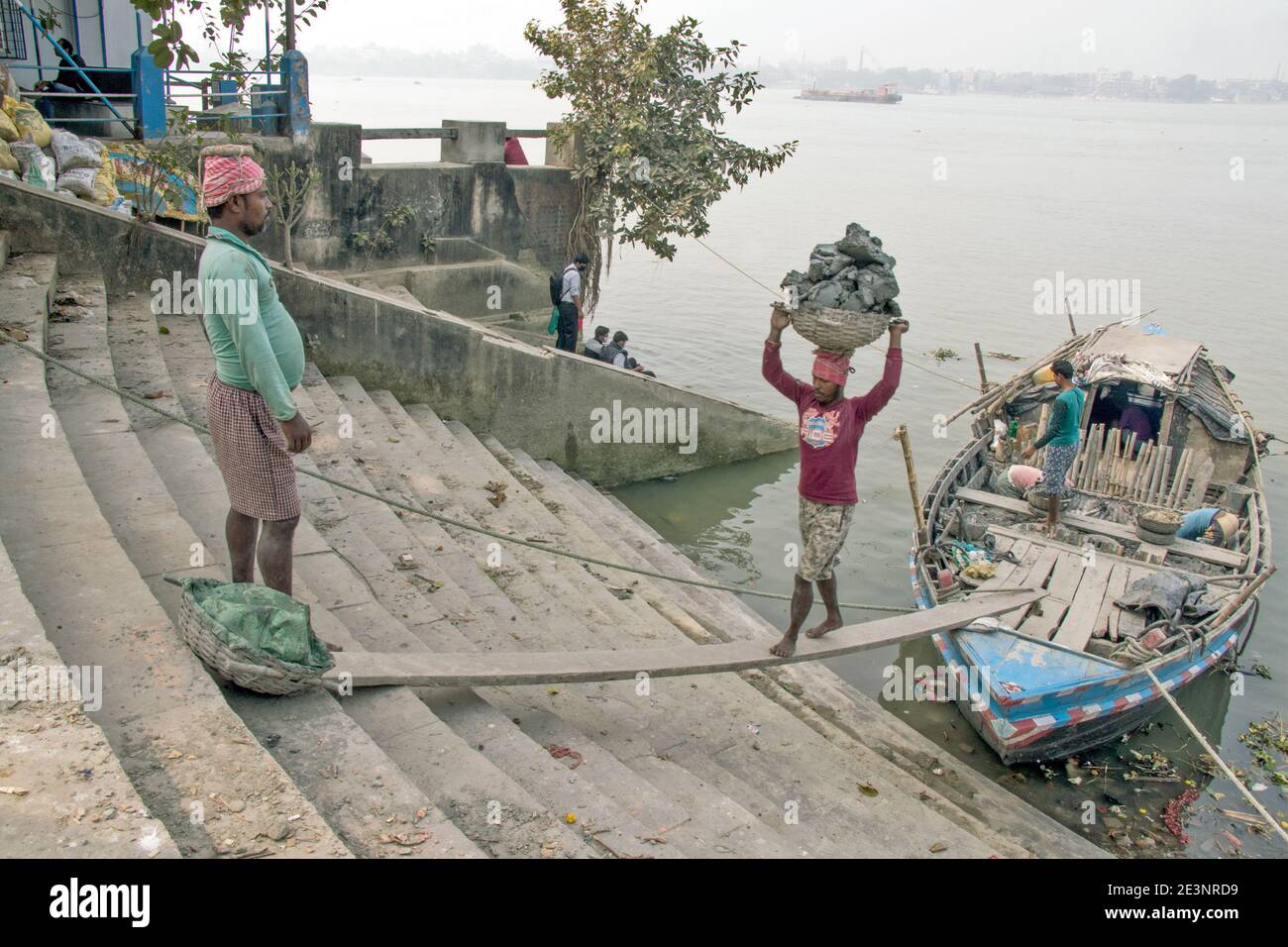 Der Schlick für die Götzenherstellung wird von einem Boot in Kumortuli Ghat entladen. Der ideale Schlamm für die Herstellung von Idolen ist Flussboden, der aus kolaghat genommen wird. Stockfoto