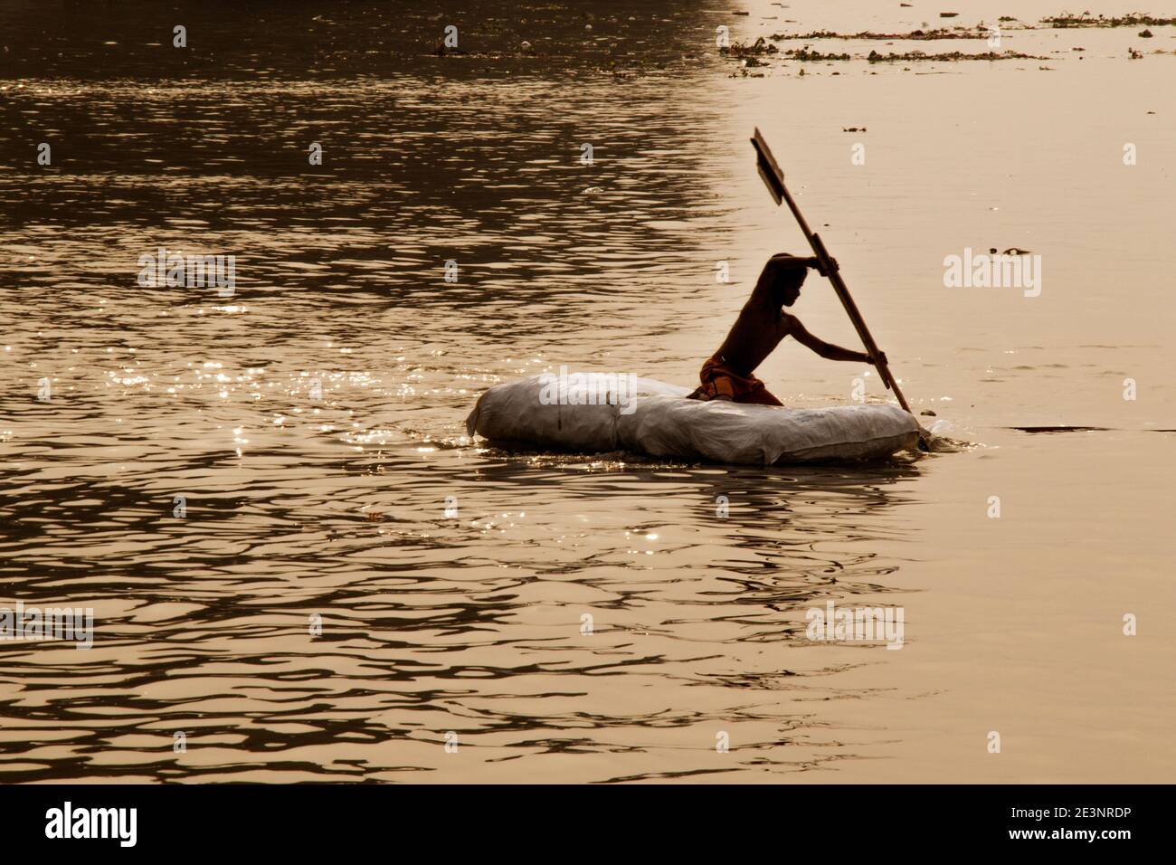 Ein kleiner Junge ist mit dem Floß auf dem Ganges in Kalkutta unterwegs. Reisen auf diesem Floß ist nur ein Teil der Kindheit. Stockfoto