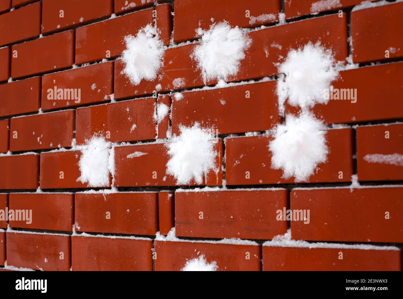 Ziegelwand mit ein paar Schneebällen darauf Stockfoto