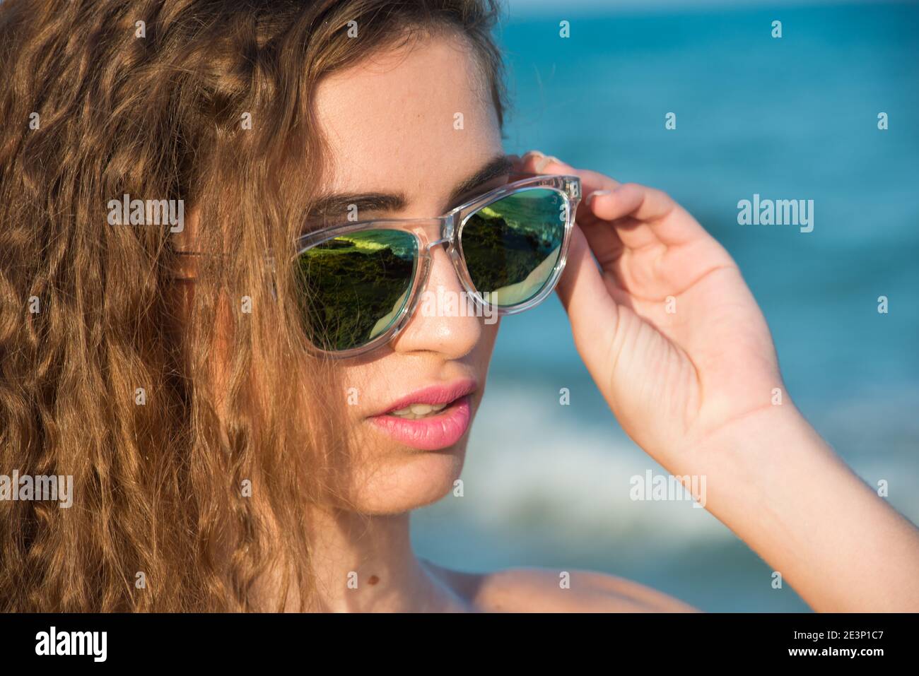 Blonde Frau mit langen lockigen Haaren genießen das Meer in Frühling oder Sommer Stockfoto