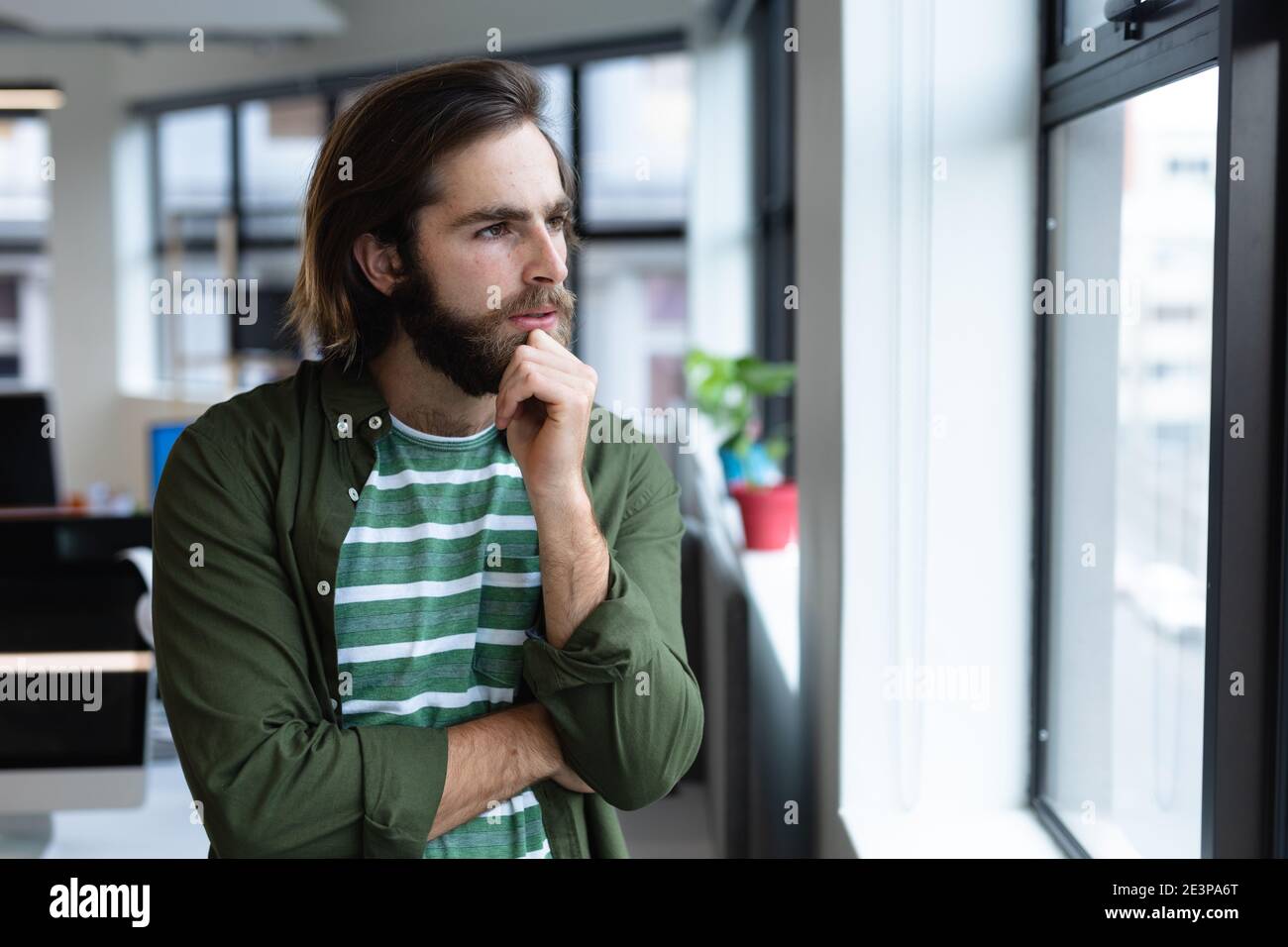 Kaukasischen Geschäftsmann in Gedanken Blick durch Fenster in kreativen Büro Stockfoto