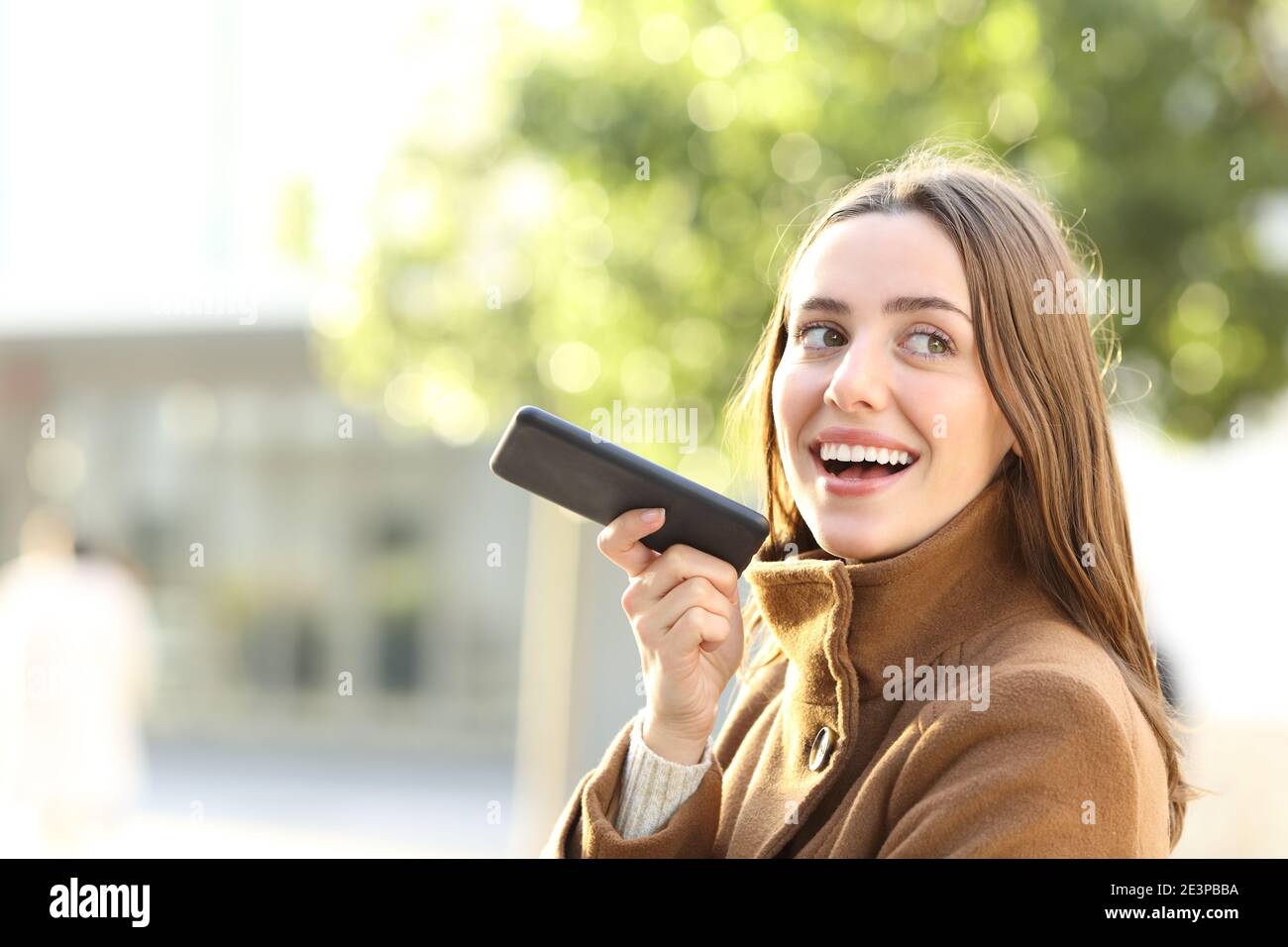 Porträt einer glücklichen Frau diktieren Nachricht auf dem Smartphone Im Winter auf der Straße Stockfoto