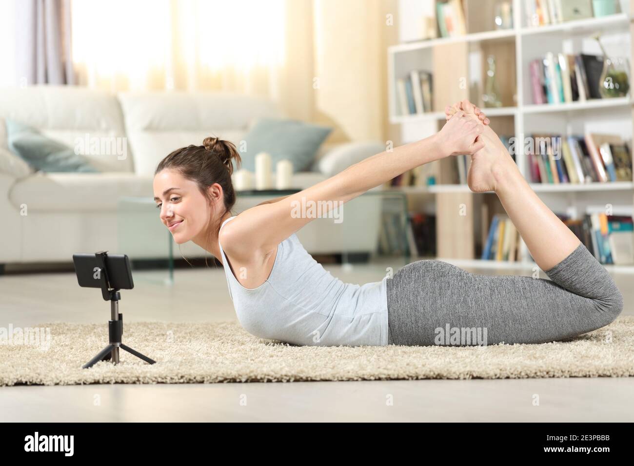 Profil von einer glücklichen Frau, die Yoga-Übung macht, das Video aufsieht Tutorial zum Smartphone zu Hause Stockfoto