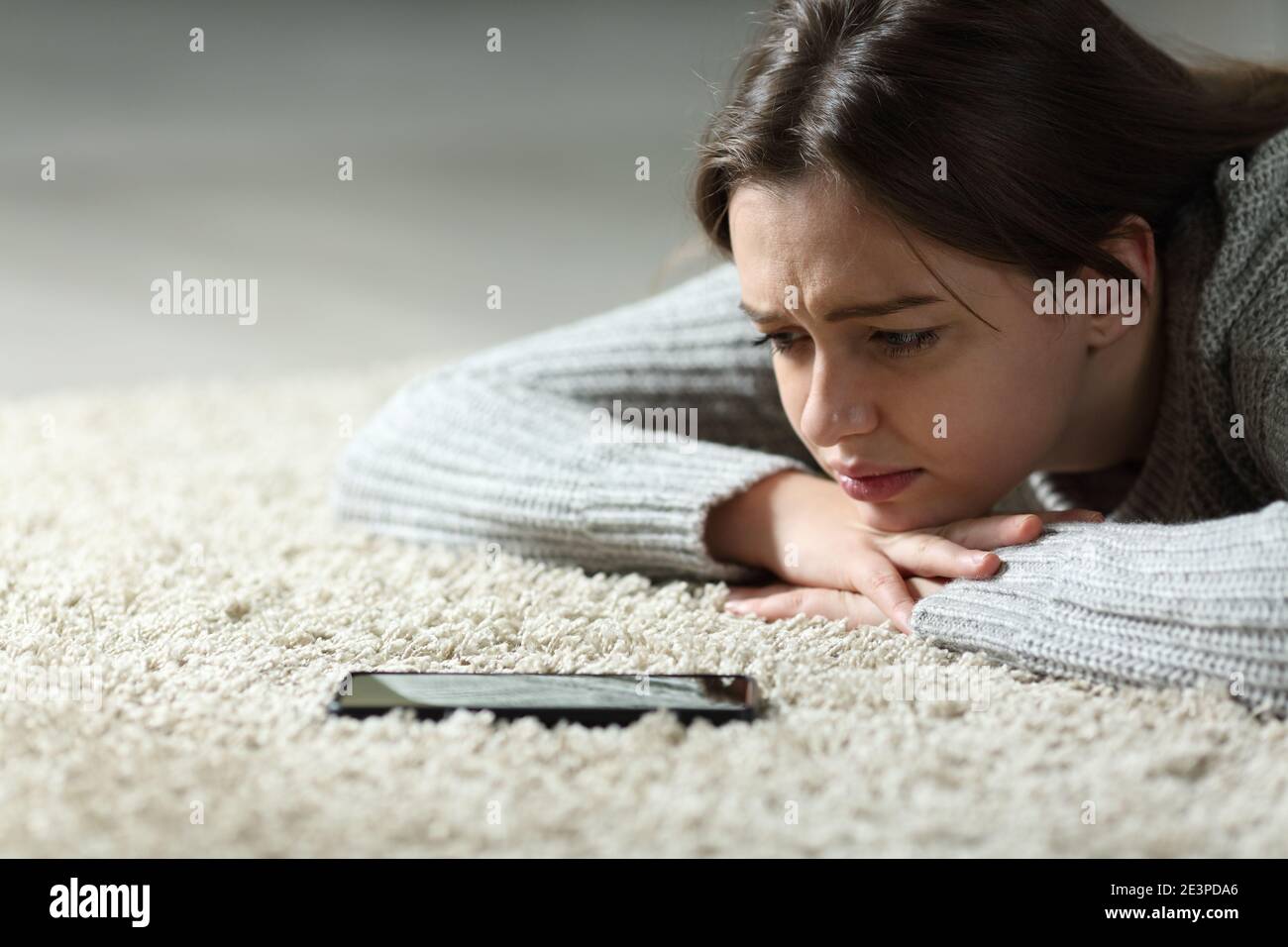 Traurige Teenager warten auf Handy-Nachricht liegen auf der Boden zu Hause Stockfoto