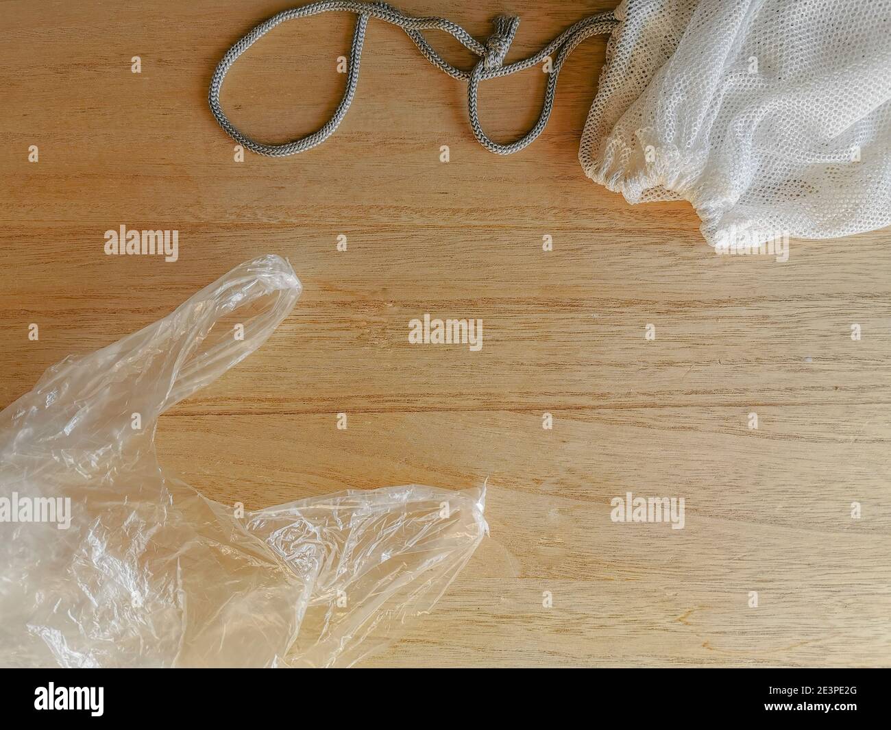 Einweg-Plastiktüte und wiederverwendbarer Gemüsebeutel als nachhaltige Lösung auf Holzhintergrund. Umweltfreundliches Konzept. Kein Waste Swap. Stockfoto