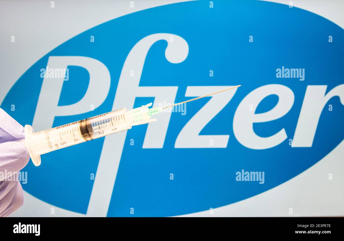 Spritze als COVID-19 Impfstoffkonzept mit dem Pfizer Logo im Hintergrund. Stockfoto
