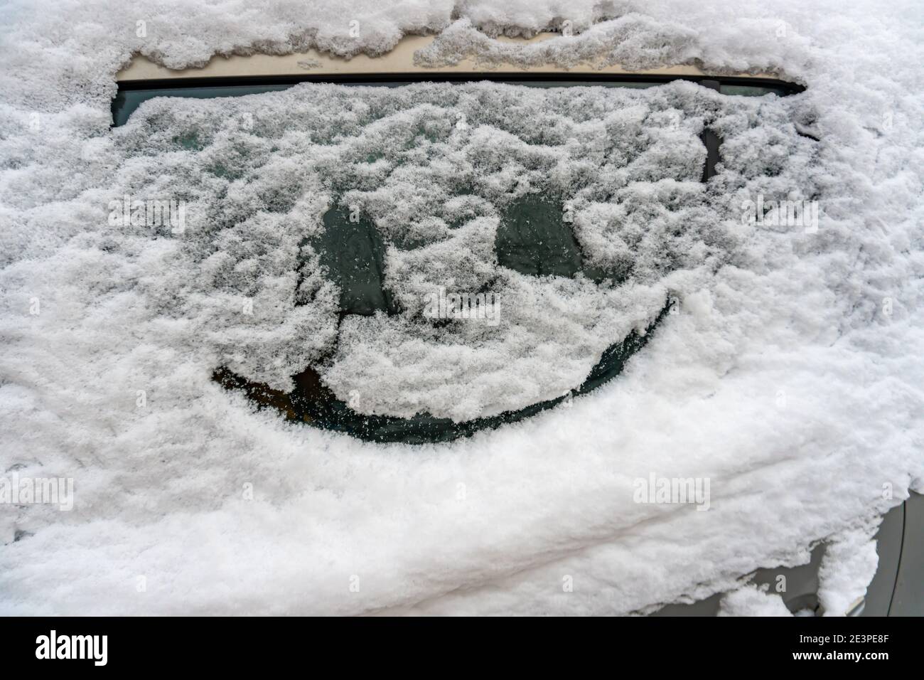 Gezeichnetes Lächeln auf Autoglas auf Schnee Stockfoto