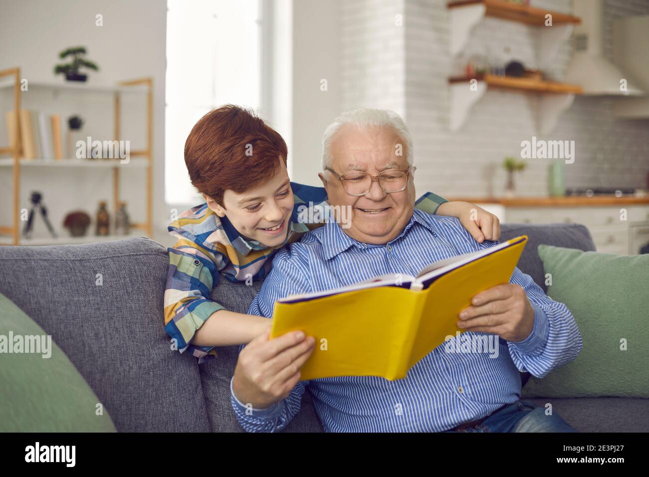 Glücklicher Großvater und Kind genießen Spaß Zeit zusammen und lesen Buchen Sie im gemütlichen Wohnzimmer Stockfoto