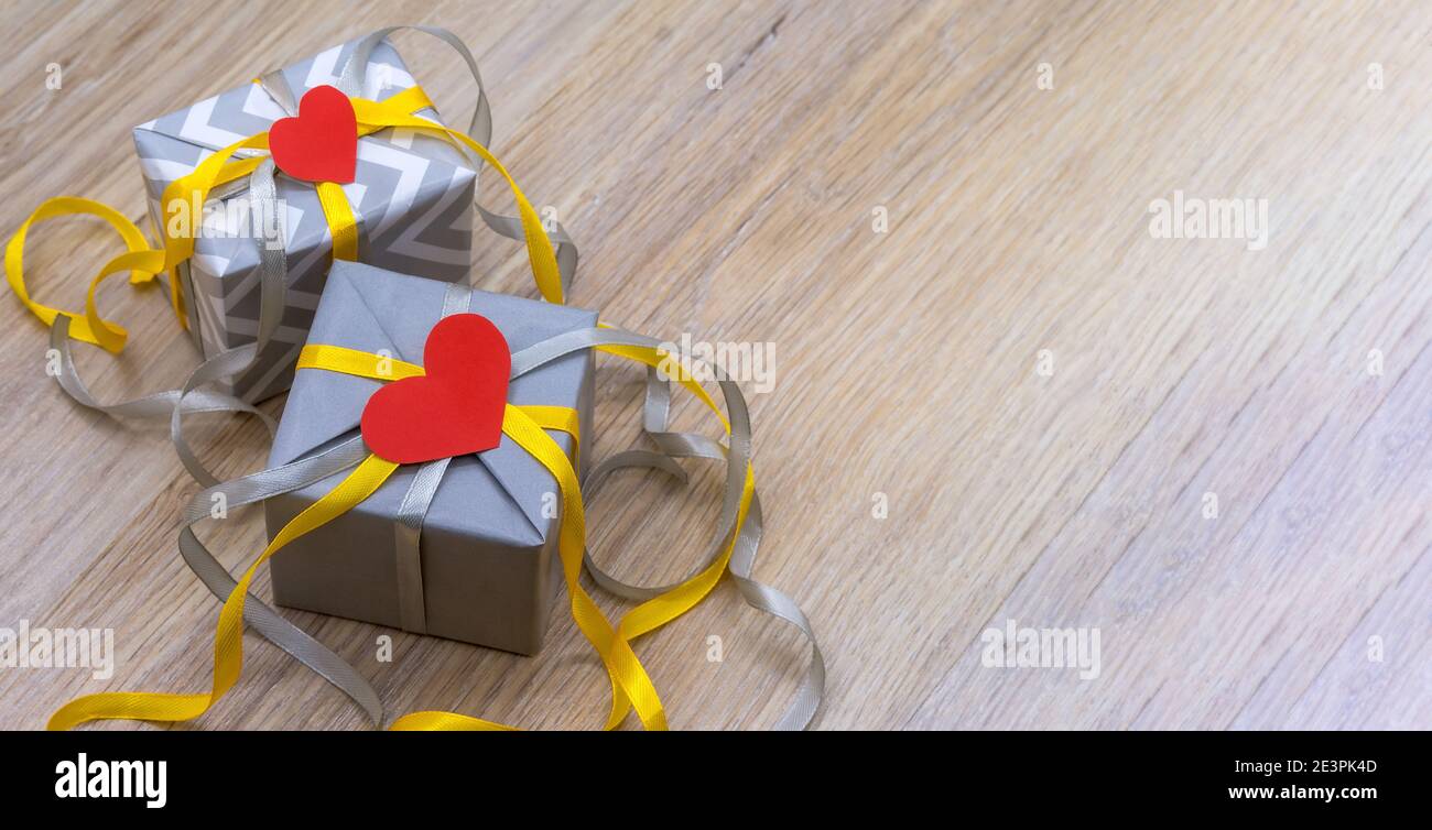 valentinstag februar 14, graues Geschenk mit gelbem Band, graue Verpackung mit rotem Band, valentinstag Dekor Stockfoto