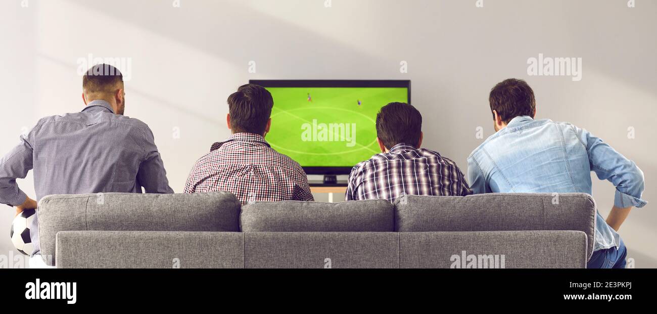 Vier Männer Freunde sitzen rückwärts auf dem Sofa zu Hause und Fußballspiel im fernsehen ansehen Stockfoto