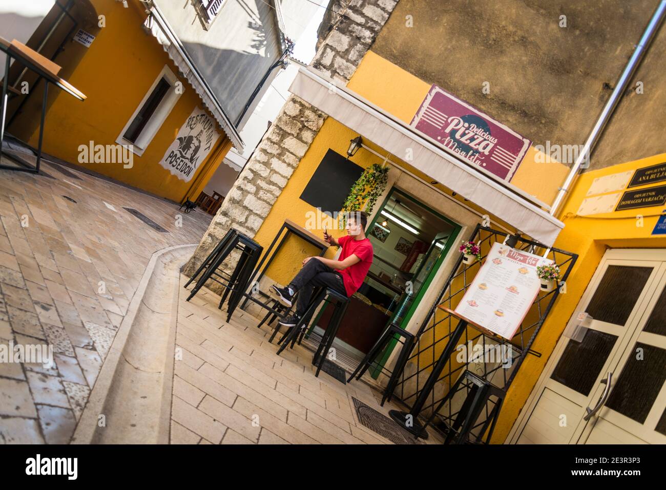 Mann sitzt in einem Café in einer engen, Fußgängerzone mit Straßencafés, Zadar, Dalmatien, Kroatien Stockfoto