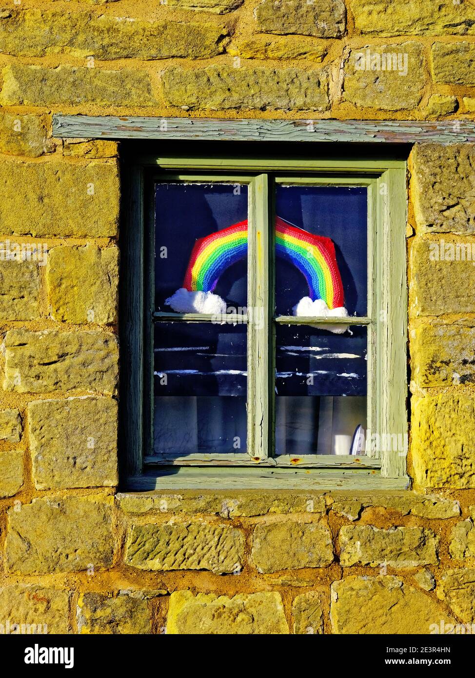 Covid-19 Regenbogen-Zeichen in Hütte Fenster mit alten Steinmauern Stockfoto