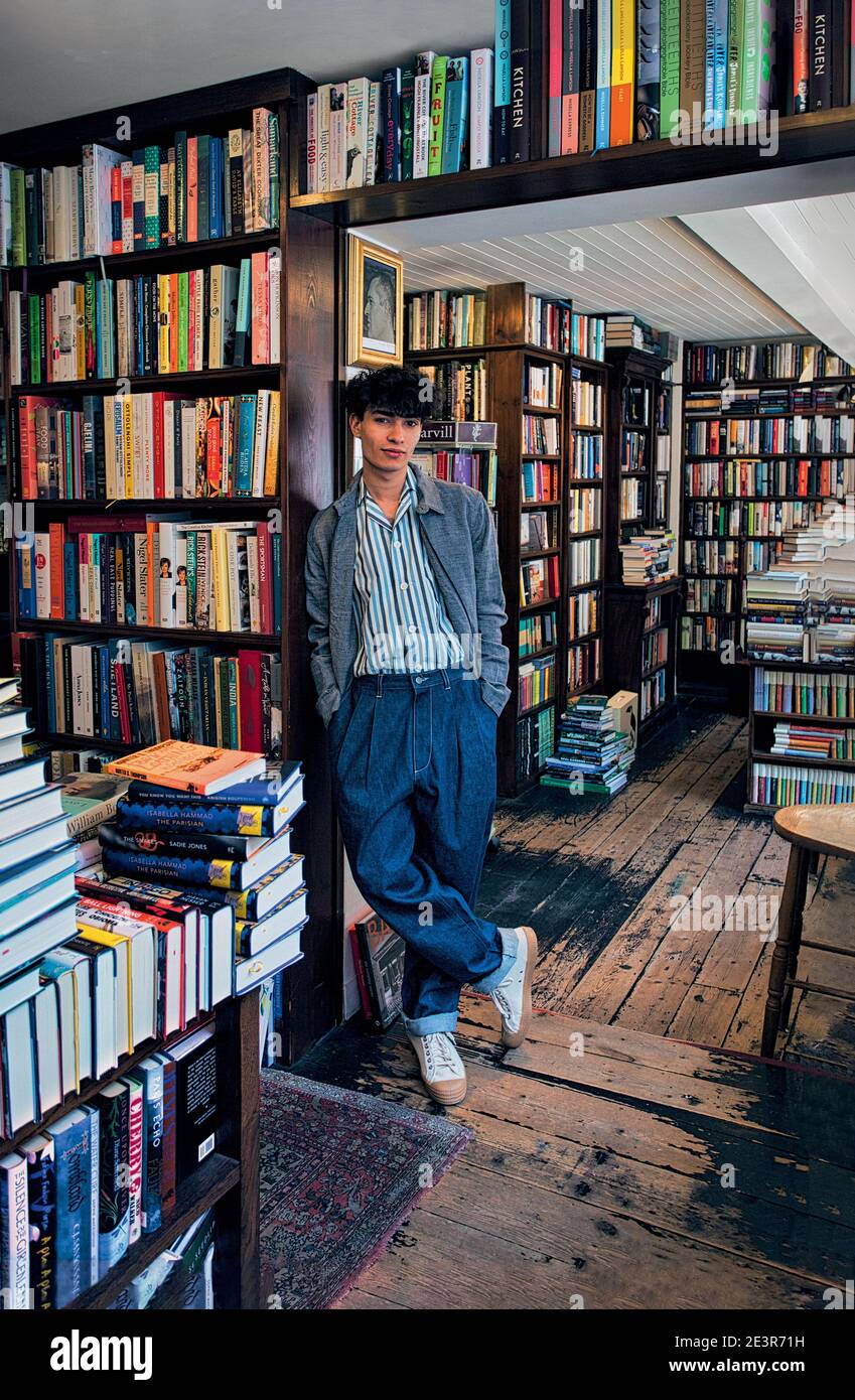 GREAT BRITAN / London /Buchhandlungen / Porträtaufnahme eines jungen Mannes, der in der Nähe des Bücherregals im Buchladen steht. Stockfoto
