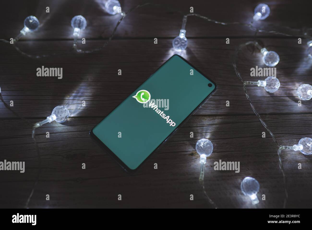 Smartphone mit Whatsapp Messenger-Zeichen und Logo auf dem angezeigt Leinwand auf schönem Holzhintergrund mit Lichtern Stockfoto